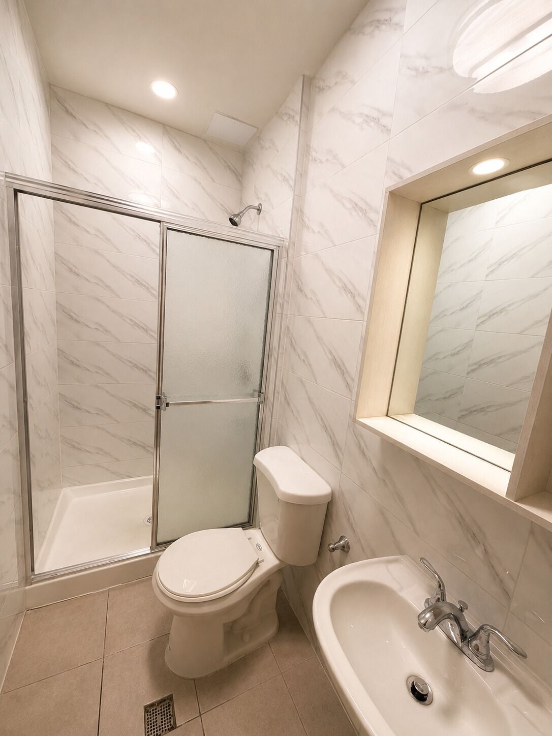 A modern bathroom with a glass-enclosed shower, a toilet, and a sink with a mirror above.