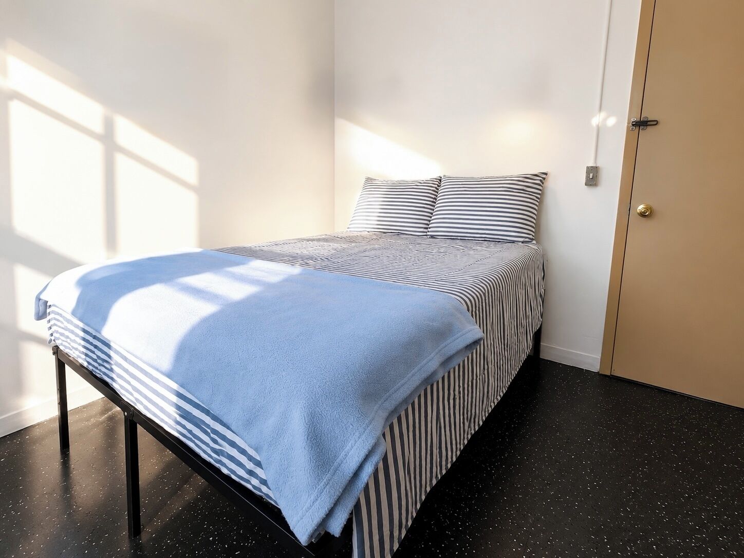 Ein Schlafzimmer mit einem Bett, einer Tür und einem Fenster.