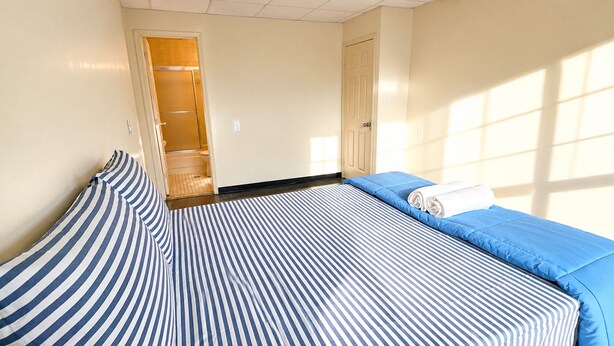 A hotel room with a bed, a blue and white striped pillow, a blue bedspread, and a rolled white towel. - 101 HOTEL Manhattan New York City (New York)