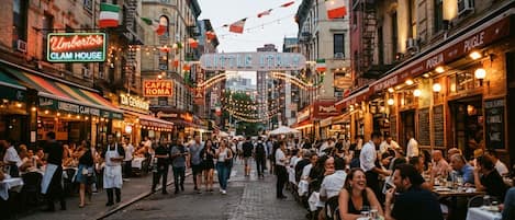 Une rue animée, avec des terrasses de restaurants, des drapeaux italiens et différents panneaux indiquant les restaurants.