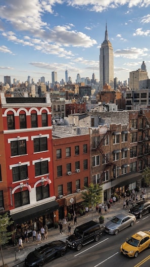 A cityscape with a prominent skyscraper in the background, a street with pedestrians, and vehicles.