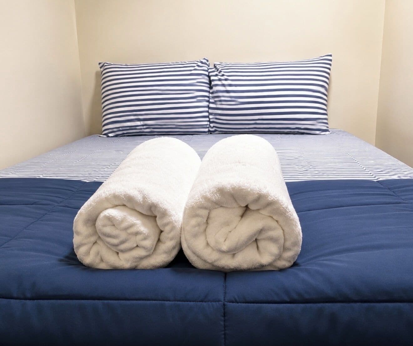 Un letto con un materasso blu e due asciugamani bianchi arrotolati sopra.