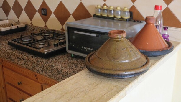 A kitchen with a gas stove, a toaster, a Moroccan tagine, and spice jars. - Seaview Apartment, Balcony, Great Location (Mirleft)