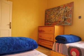 A bedroom with two beds, a wooden dresser, and a painting on the wall. - Seaview Apartment, Balcony, Great Location (Mirleft)