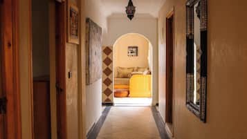 Un couloir menant à une chambre à coucher, où se trouvent un lit, un miroir et un mur décoré d’un motif.