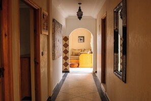 A hallway leading to a bedroom with a bed, a mirror, and a patterned wall. - 3 Bed, Seaview Apartment, Roof Terrace (Mirleft)