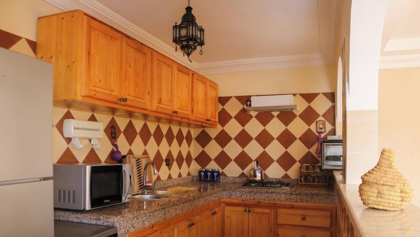 A kitchen with wooden cabinets, a microwave, a stove, and a sink.