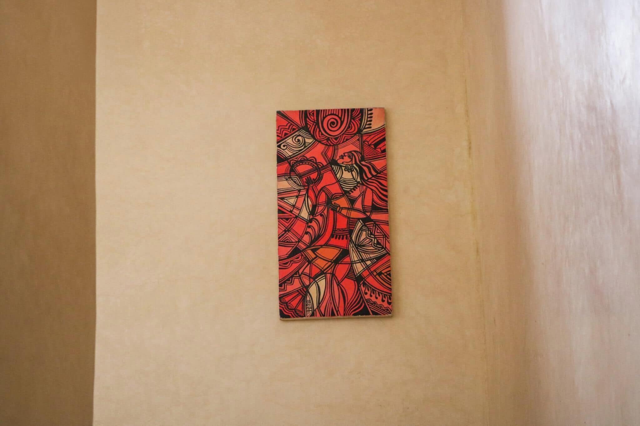 A red abstract painting on a beige wall.