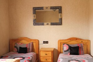 A bedroom with two beds, a nightstand, a mirror, and a wall socket. - 3 Bed, Seaview Apartment, Roof Terrace (Mirleft)