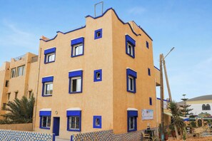 Un edificio de varios pisos con fachada plana, múltiples ventanas y un letrero que indica un negocio o servicio.