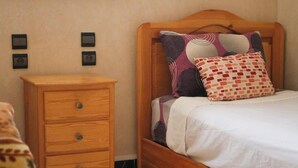 A bedroom with a wooden bed, a nightstand, and a patterned pillow.