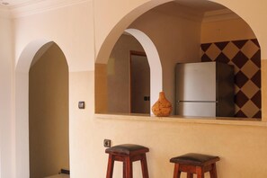A kitchen with a refrigerator, a woven basket, and two wooden stools.