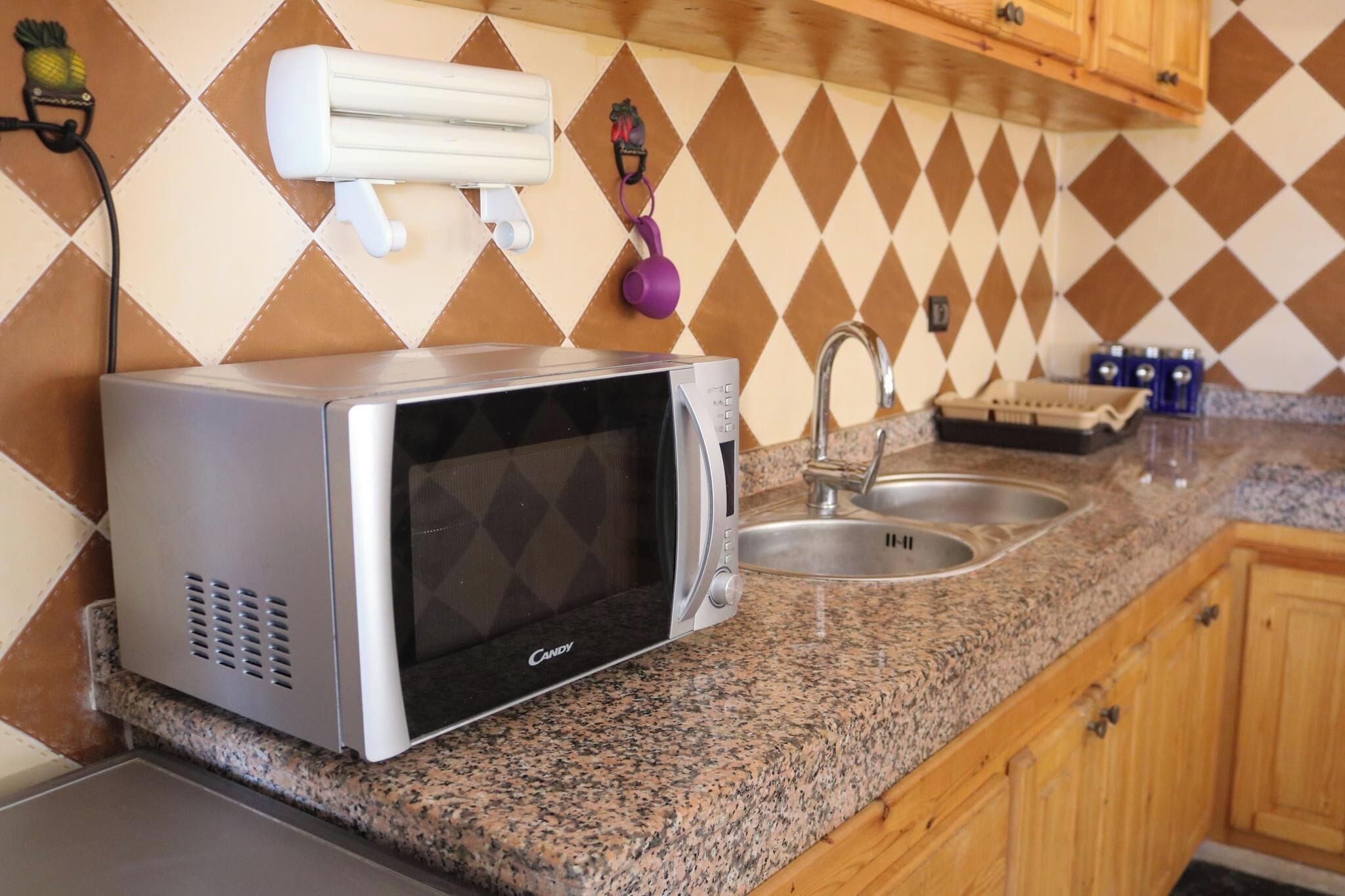 A kitchen with a microwave, sink, and granite countertop.