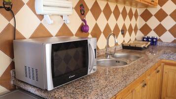 A kitchen with a microwave, sink, and granite countertop.