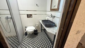 Um banheiro pequeno com vaso sanitário, pia e chuveiro.