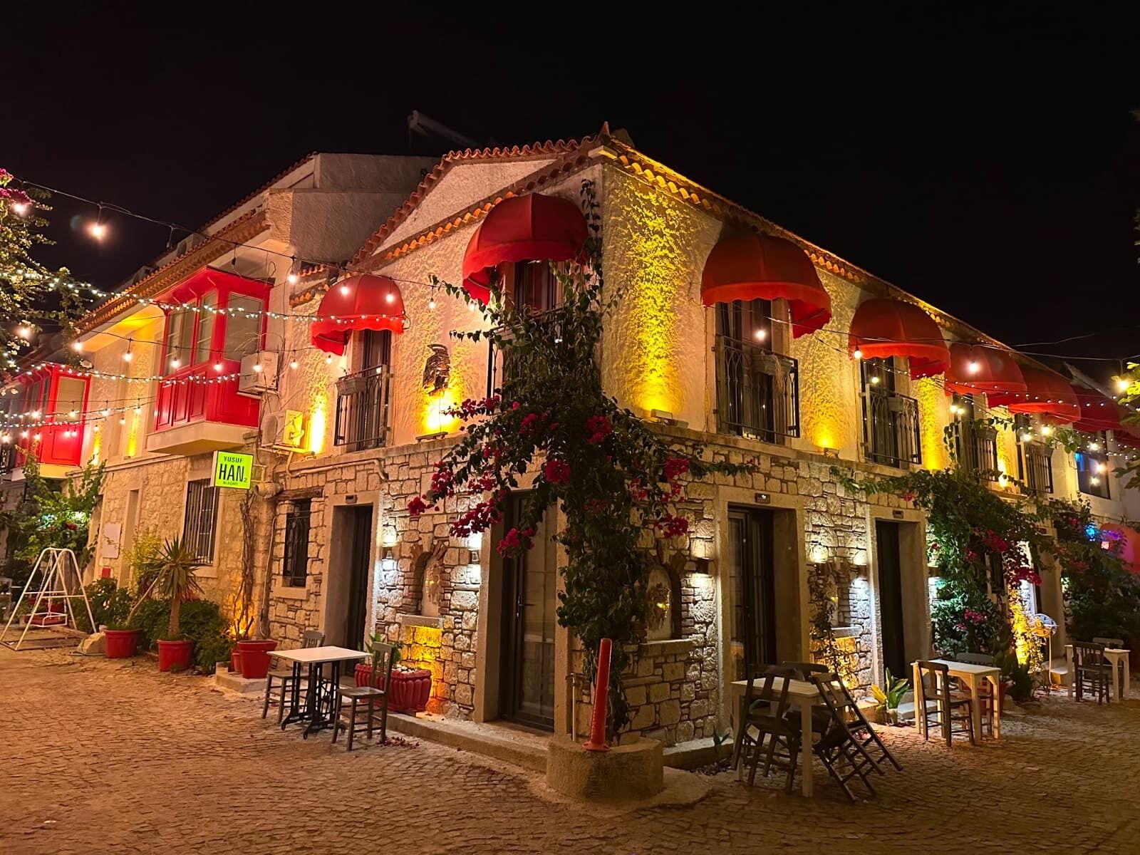 A stone building with red awnings and outdoor seating.