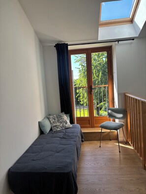 A bedroom with a bed, a chair, a balcony with a railing, and a skylight. - New vacation rental with a pool in an authentic Poitevin farmhouse (Savigny-sous-Faye)