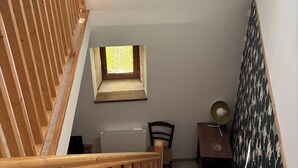 Eine Holztreppe mit einem kleinen Fenster, einem gerahmten abstrakten Kunstwerk und einer Wand mit Muster.