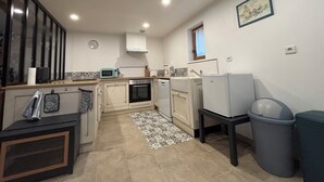 Eine kleine Küche mit Mikrowelle, Backofen und Spüle. Ein kleines Fenster und eine Uhr sind an der Wand angebracht.