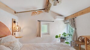 A bedroom with a bed, a window, a potted plant, and a wooden chair. - Holiday Home 'Maison En Pierre Chevaux' with Wi-Fi (Puyvert)