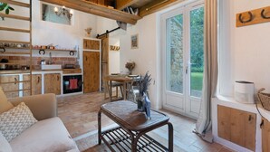 A cozy interior with a wooden ceiling, a dining area, a kitchen with copper cookware, and a large sliding glass door to the outdoors. - Holiday Home 'Maison En Pierre Chevaux' with Wi-Fi (Puyvert)