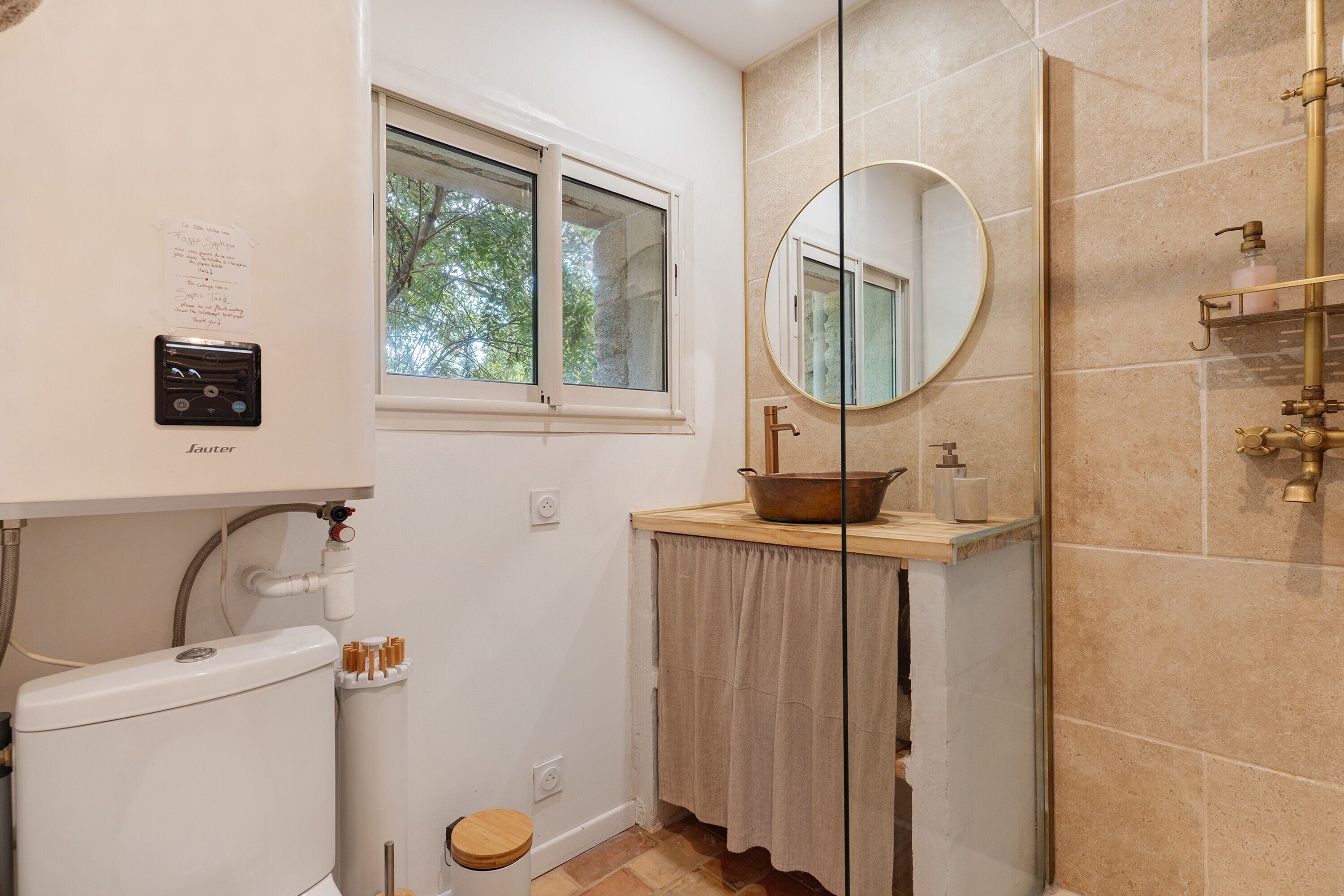 Une salle de bain comprenant des toilettes, une fenêtre, un miroir, un lavabo et un espace douche.