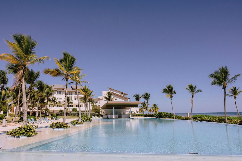 A resort with a swimming pool, palm trees, and beachfront views.