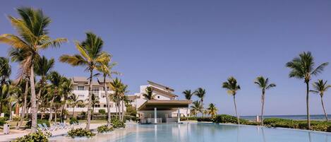 Un resort con piscina, palmeras y vistas a la playa.