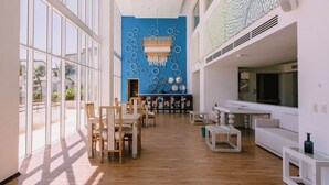 Un interior espacioso con amplias ventanas, una pared de acento azul y un comedor con mobiliario de madera.