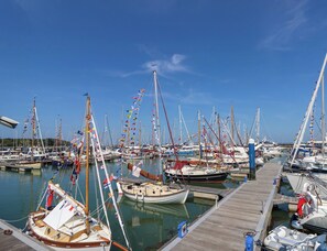 A marina with multiple boats docked, a wooden pier, and a clear blue sky. - Merrilees (Yarmouth)