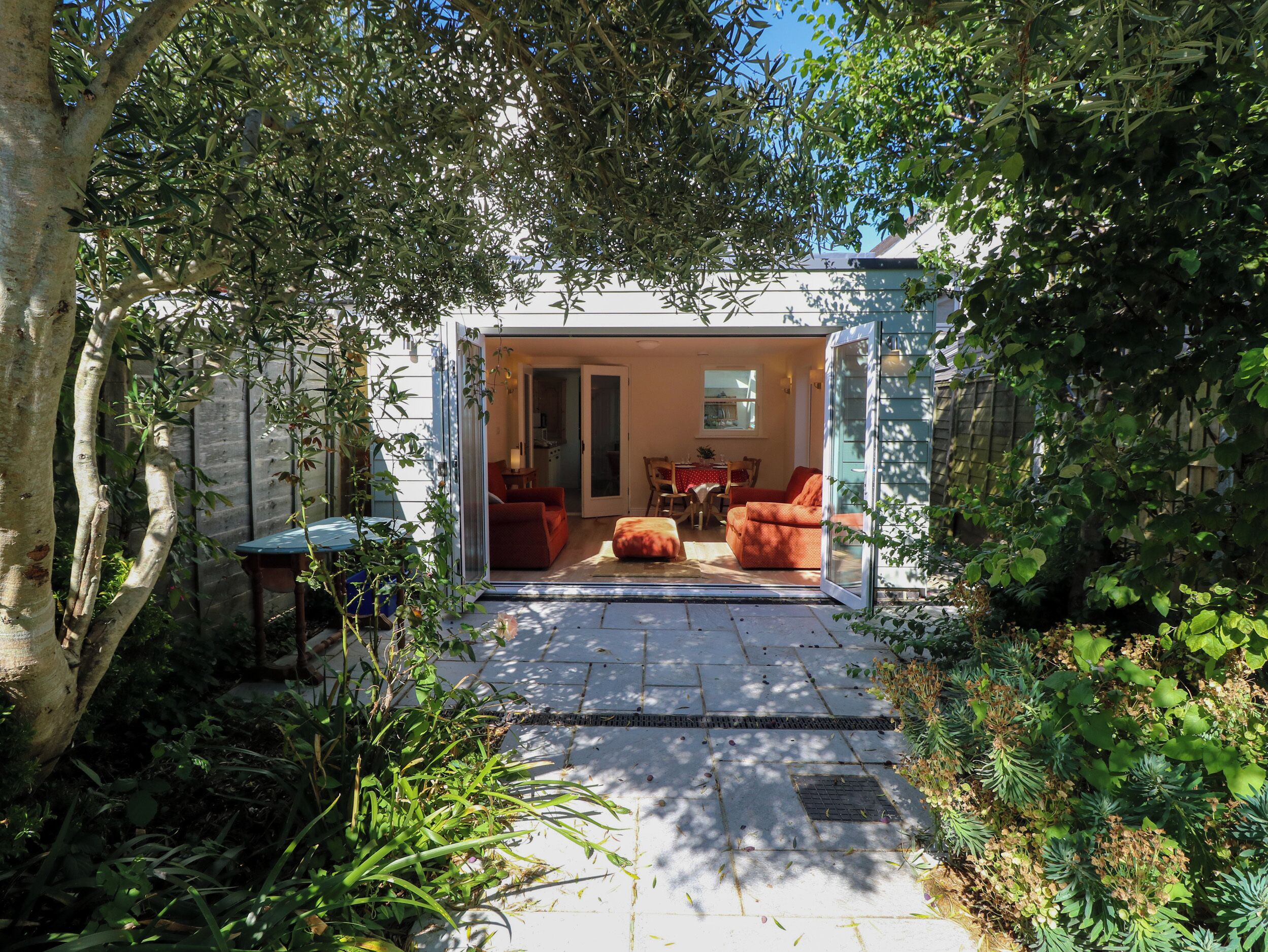 A covered outdoor patio with a seating area, a table, and a view into a room with a door.