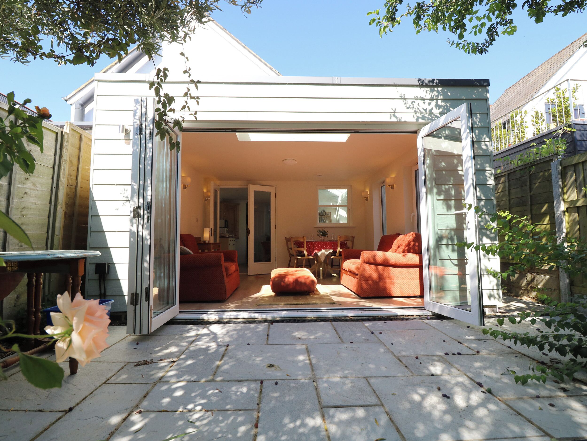 Une terrasse ouverte comprenant un coin repas, un canapé et un fauteuil.
