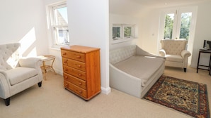 A bedroom with a bed, a chair, a dresser, and a window. - Merrilees (Yarmouth)