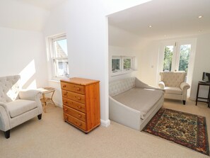 Ein Schlafzimmer mit Bett, Sessel, Kommode und Fenster.