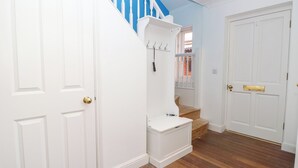 A hallway with white doors, a blue staircase, and a wooden floor. - Merrilees (Yarmouth)