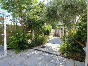 Eine gepflasterte Terrasse mit Holzlattenzaun, umgeben von üppigem Grün und Bäumen.