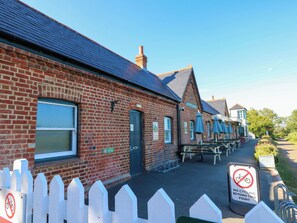 A brick building with a green door, outdoor seating, and a no cycling sign. - Merrilees (Yarmouth)