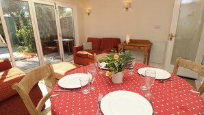 A dining area with a red polka dot tablecloth, white plates, cutlery, and a vase with flowers. - Merrilees (Yarmouth)