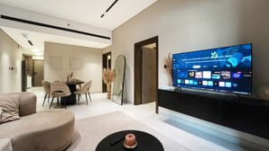 Ein modernes Wohnzimmer mit Flachbildfernseher, Essbereich und einer Couch.