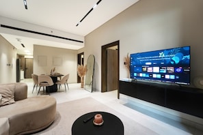 Ein modernes Wohnzimmer mit Flachbildfernseher, Essbereich und einer Couch.
