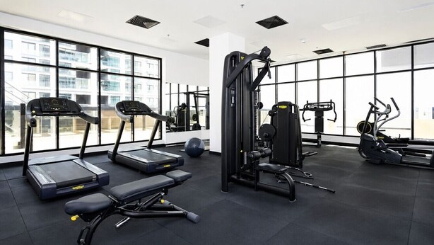 Ein Fitnessstudio mit Laufbändern, einer Hantelbank und Krafttrainingsgeräten.