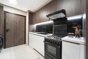 Une cuisine moderne équipée d’une cuisinière à gaz, d’un four et d’appareils électroménagers en acier inoxydable.