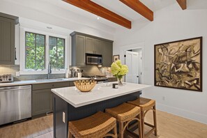 A modern kitchen with grey cabinets, a large island, and a painting on the wall. - (2027 OPEN!) Gorgeous Union Pier Home With Private Pool! (Union Pier)