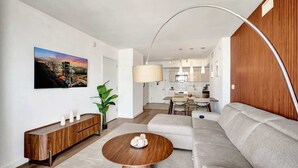 Un salon moderne avec un canapé, une table basse, une console en bois et un tableau représentant un paysage urbain.