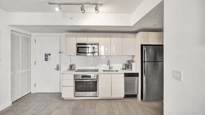 Une cuisine moderne avec des armoires blanches, des appareils en acier inoxydable et un plancher en bois clair.
