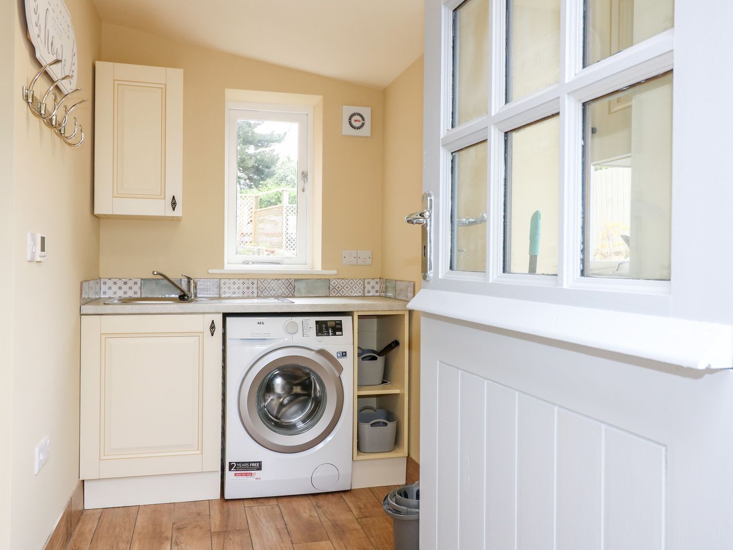 A compact kitchen with a built-in washing machine, a window with a view, and a radiator.