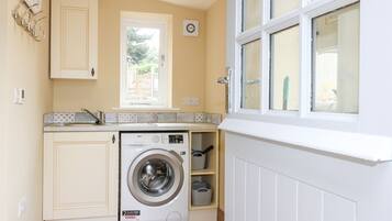 A compact kitchen with a built-in washing machine, a window with a view, and a radiator.