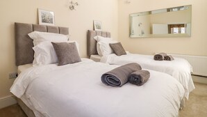 A hotel room with two beds, a skylight, a large mirror, and a radiator. - Churn Dash Cottage (Derby)