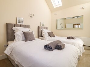 Ein Hotelzimmer mit zwei Betten, einem Oberlicht, einem großen Spiegel und einer Heizung.