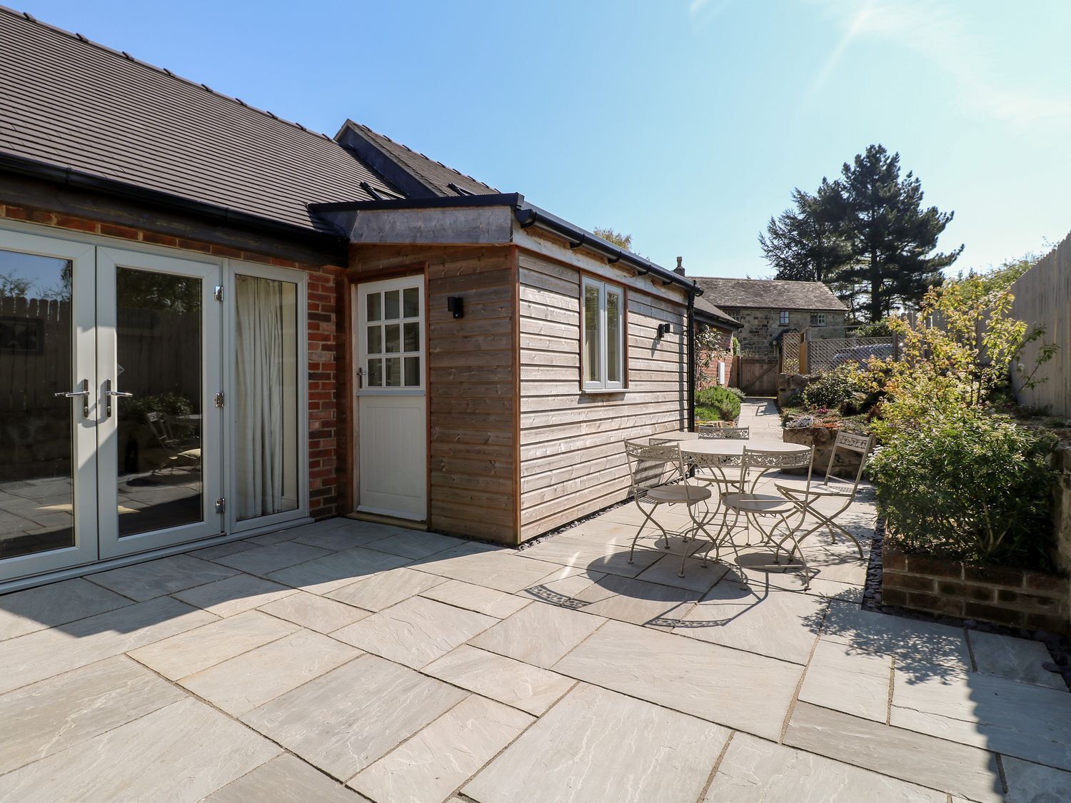 Een huis met een terras, een schuifpui en een kleine tuin.